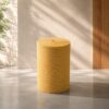 Rollo de lana de vidrio térmica de 14 kg/m3 color amarillo colocado verticalmente sobre un fondo arquitectónico minimalista.